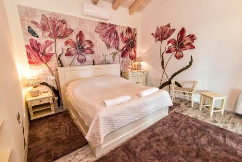a bedroom with a bed with flowers on the wall at Villa Terazza-Panorama Apartman in Sümeg