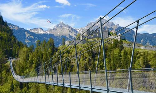 a suspension bridge over a river with mountains in the background at Pension Posthansl in Heiterwang