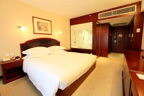 a bedroom with a large bed with white sheets and pillows at Beijing Landmark Towers in Beijing