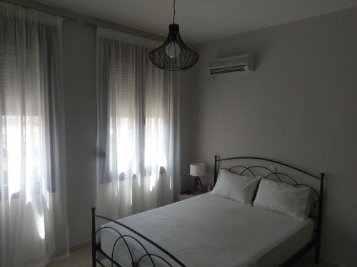 a bedroom with a bed with white sheets and a window at Prokymaia Apartment 2 in Áyios Andónios