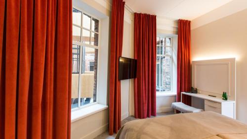 a bedroom with red curtains and a bed and a window at Park Hotel Viljandi in Viljandi