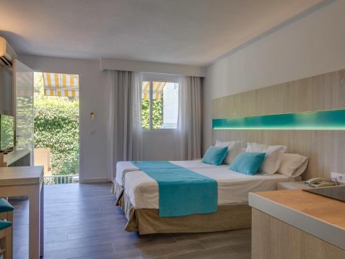 a bedroom with a large bed with blue pillows at Comitas Floramar in Cala Galdana