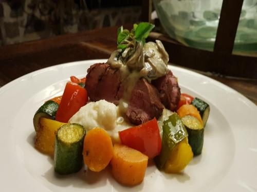 a plate of food with meat and vegetables on a table at Tutwa Desert Lodge in Augrabies
