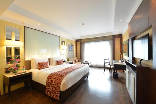 a hotel room with a large bed and a television at Ramada Plaza Chennai in Chennai