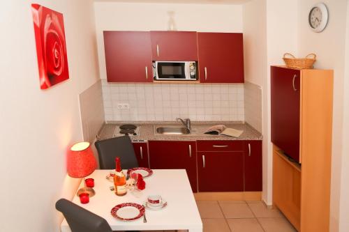 キュールングスボルンにあるStrandschlösschen Appartement 19の小さなキッチン(赤いキャビネット、白いテーブル付)