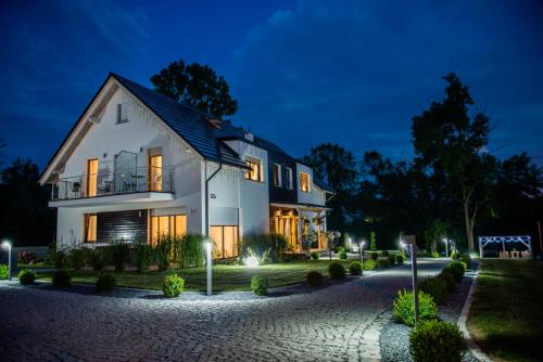 una gran casa blanca por la noche con luces en Apartamenty u Harrego II Przy Stawie Spa en Kudowa-Zdrój