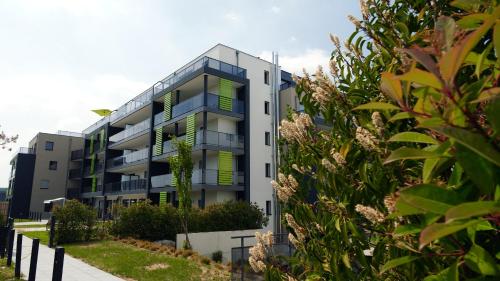 an apartment building with green windows and bushes at Aparthotel Adagio Bâle Mulhouse Aeroport in Blotzheim
