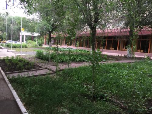 a garden in front of a building with trees at Гостиница ИЛЕК in Aktobe