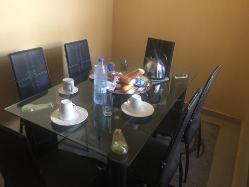 a glass table with a plate of food and water bottles at Maison d'Hôtes entière Cité Douane Golf Dakar in Dakar