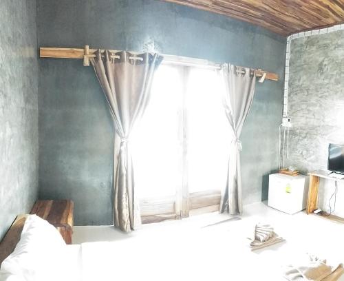 a bedroom with a window with curtains on the wall at Teak villa in Thoeng