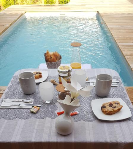 une table avec de la nourriture et des boissons à côté d'une piscine dans l'établissement L'Essentiel, à Gujan-Mestras
