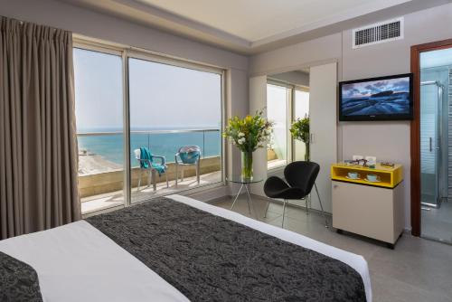 a hotel room with a bed and a view of the ocean at Arena Hotel by the Beach in Bat Yam