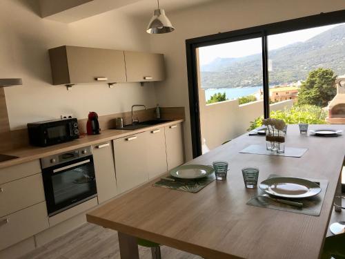 a kitchen with a wooden table and a large window at Appartement 80m2 dans Villa in Propriano