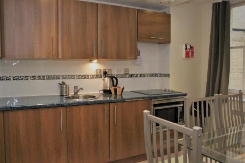 a kitchen with wooden cabinets and a sink at Grand Plaza Serviced Apartments in London