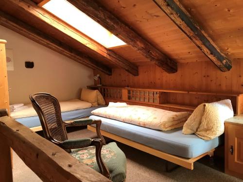 ein Zimmer mit 3 Betten und einem Stuhl darin in der Unterkunft B&B Hotel & Appartements Chasa Valär in Scuol