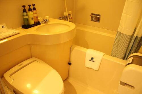 a bathroom with a white toilet and a sink at HOTEL LiVEMAX BUDGET Kagoshima in Kagoshima