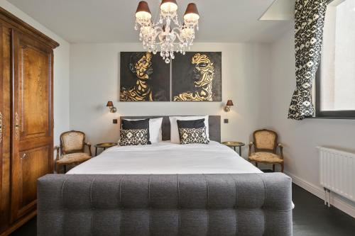 1 dormitorio con 1 cama con lámpara de araña y sillas en Puur B&B, en Amberes