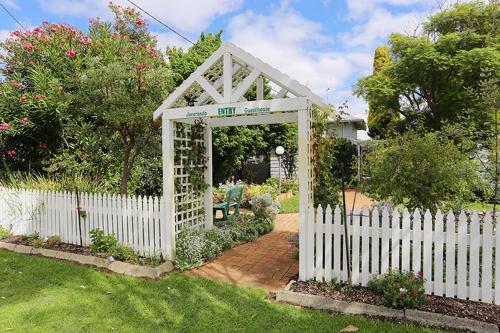 
a garden area with a wooden fence and a garden hose at Jacaranda Guest House in Busselton
