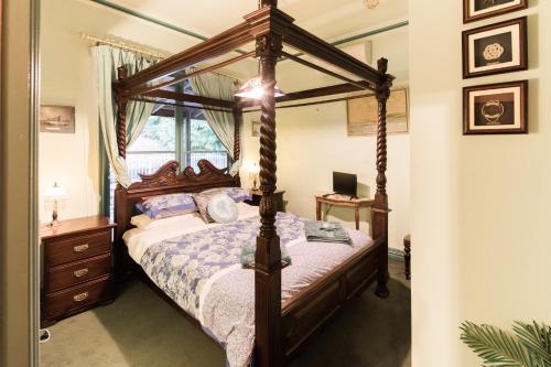 Rustic Refuge Guesthouse في Kalorama: غرفة نوم مع سرير المظلة ومكتب