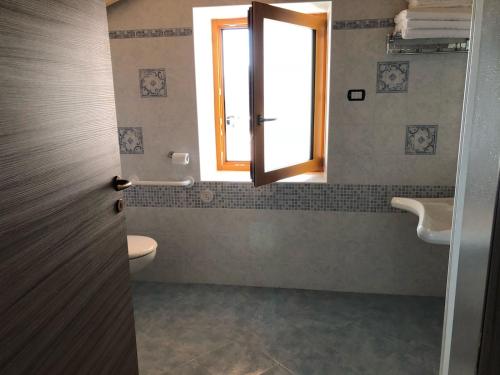 a bathroom with a toilet and a sink and a window at B&B Butterfly in Bresimo