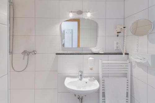 W białej łazience znajduje się umywalka i lustro. w obiekcie INVITE Hotel Löwen Freiburg we Fryburgu Bryzgowijskim