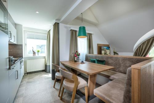 a kitchen and dining room with a wooden table and chairs at Aktiv- & Gesundheitsresort das GXUND - Thermeneintritt inklusive in Bad Hofgastein