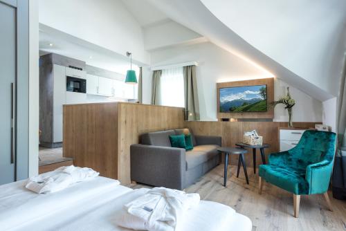 a hotel room with a bed and a couch and a chair at Aktiv- & Gesundheitsresort das GXUND - Thermeneintritt inklusive in Bad Hofgastein