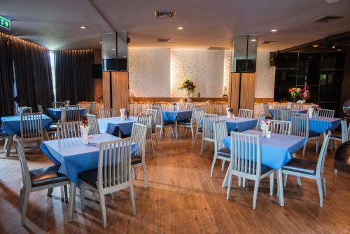 uma sala de jantar com mesas azuis e cadeiras brancas em Mantra Varee Hotel em Khon Kaen