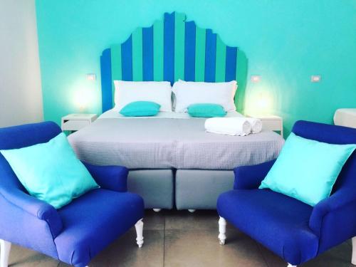 a bedroom with a bed and two blue chairs at Casa Lucia in Sorrento