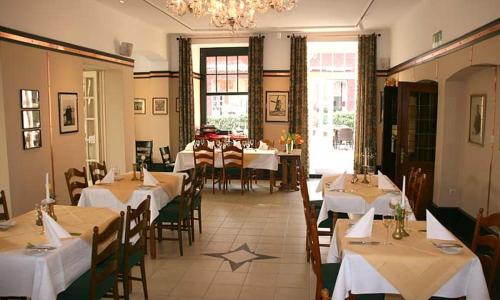 un ristorante con tavoli e sedie bianchi e un lampadario di Mutter Siepe a Lüdinghausen
