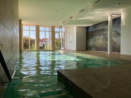 an indoor swimming pool with water in a building at Familie beachhuis op de duinen (Duinhuis) in Cadzand