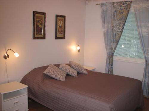 a bedroom with a bed with two pillows and a window at Kohtalo Travel Villa - Rautalampi in Hankamäki