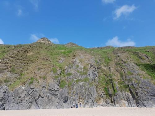 people standing on the beach next to a mountain at The Rusty Mackerel in Teelin