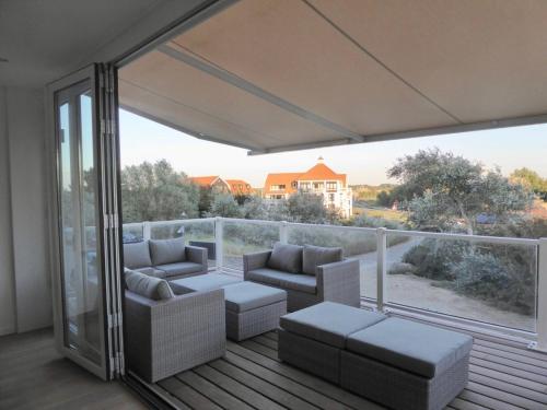 a balcony with couches and a view of a house at Familie beachhuis op de duinen (Duinhuis) in Cadzand