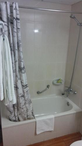 y baño con bañera y cortina de ducha. en Hostal Casa Palmira, en Espot