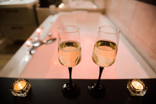 - deux verres de champagne assis sur une baignoire dans l'établissement La Suite Romantique avec Jacuzzi au Cœur de Perpignan, à Perpignan