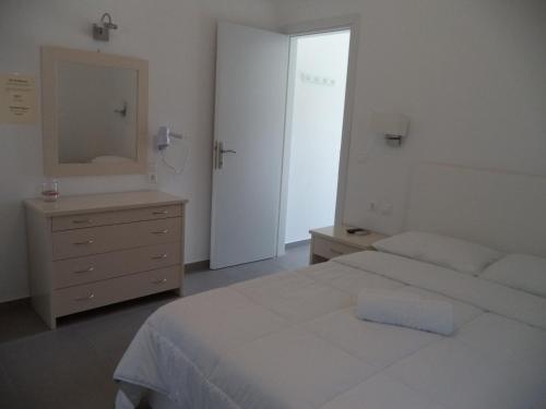 a bedroom with a bed and a dresser and a mirror at Taxiarchis Studios in Áyios Yeóryios