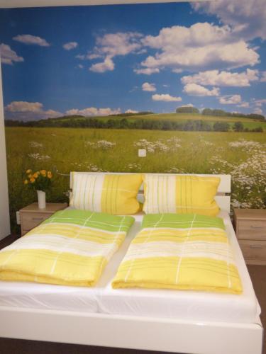 Una cama blanca con almohadas amarillas y un campo de flores. en Ferienhaus Tamm-Voß en Grömitz