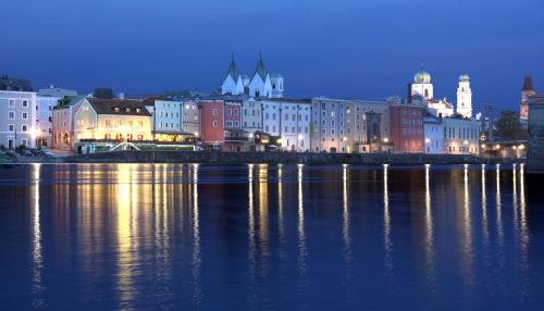 a city at night with the lights on the water at Altstadt-Hotel Passau in Passau