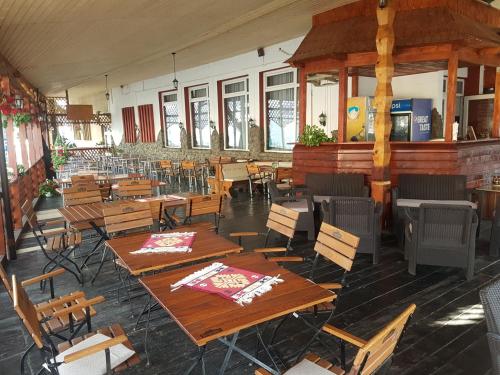 an empty restaurant with wooden tables and chairs at Pensiunea Mioritza in Horezu