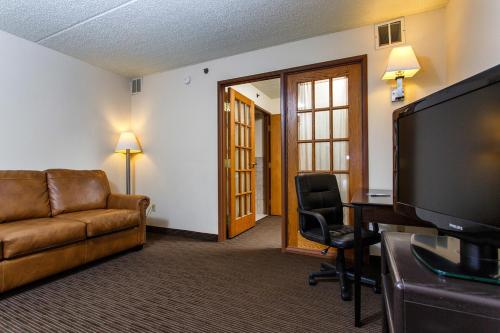 a hotel room with a couch and a desk and a television at AmericInn by Wyndham Green Bay West in Green Bay