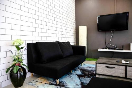 a living room with a black couch and a tv at Sibu Swanhouse No.3 in Sibu