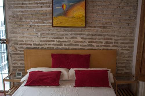 a bedroom with a brick wall and a bed with red pillows at Casa histórica Gines in Ginés