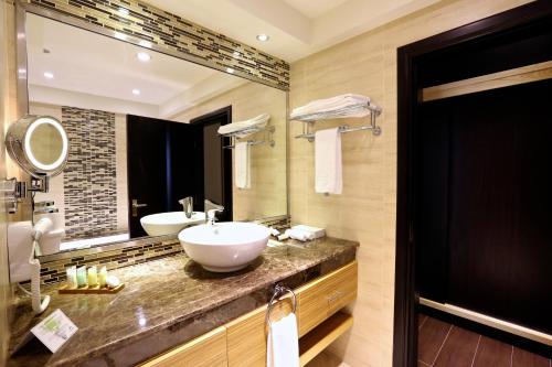 une salle de bain avec deux lavabos et un grand miroir dans l'établissement Nehal Hotel, à Abu Dhabi
