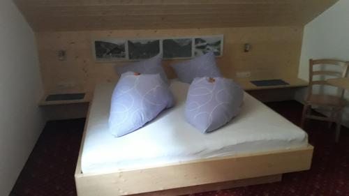 a bed with white sheets and pillows on it at Pension Backstuba in Partenen