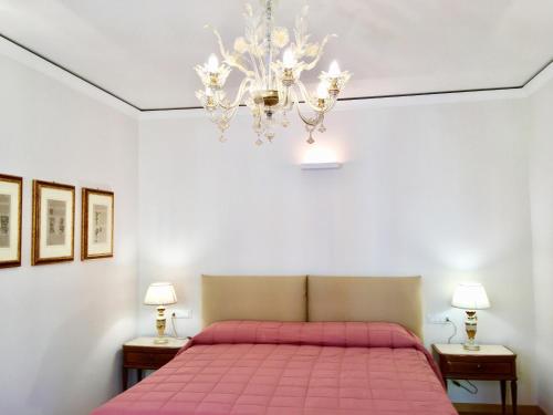 ein Schlafzimmer mit einem rosa Bett und einem Kronleuchter in der Unterkunft Casa Margherita Accademia in Venedig