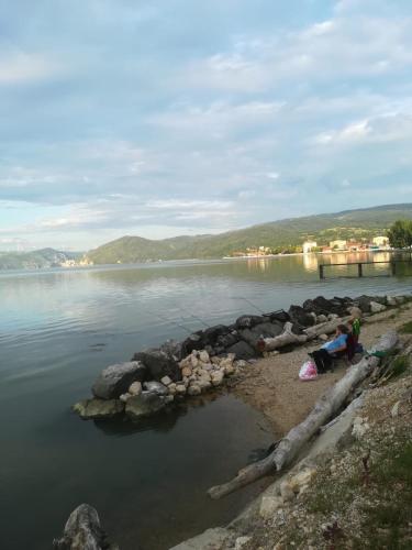 two people sitting on the shore of a body of water at Apartman Bogić in Golubac