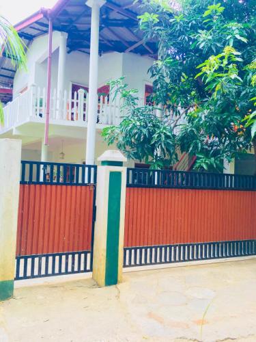 a red fence in front of a house at Sudu Neluma Home Stay in Polonnaruwa