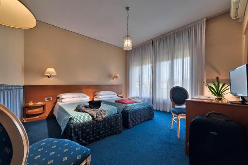 a hotel room with two beds and a television at Hotel Grand Torino in Abano Terme