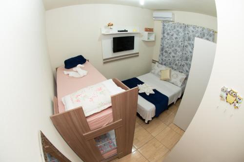 a small room with two beds and a tv at Pousada Fiedler E Anacleto in Penha